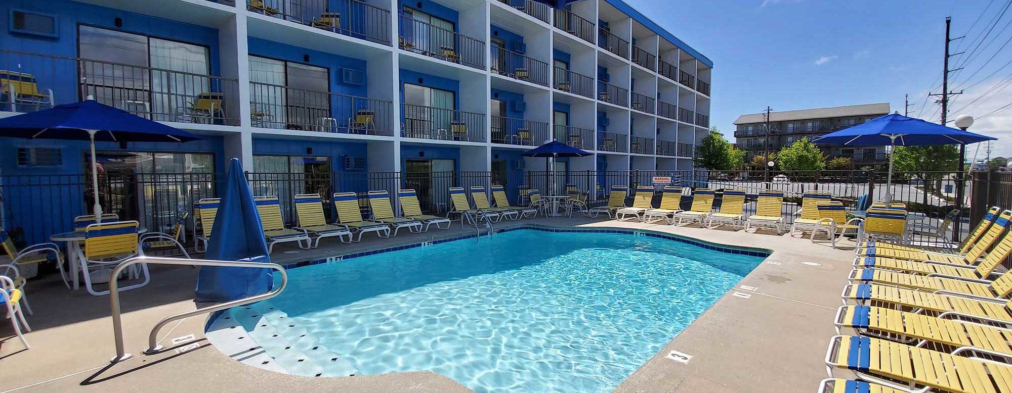 Outdoor pool balcony at the Sea Hawk motel with yellow lounge chairs and blue umbrellas